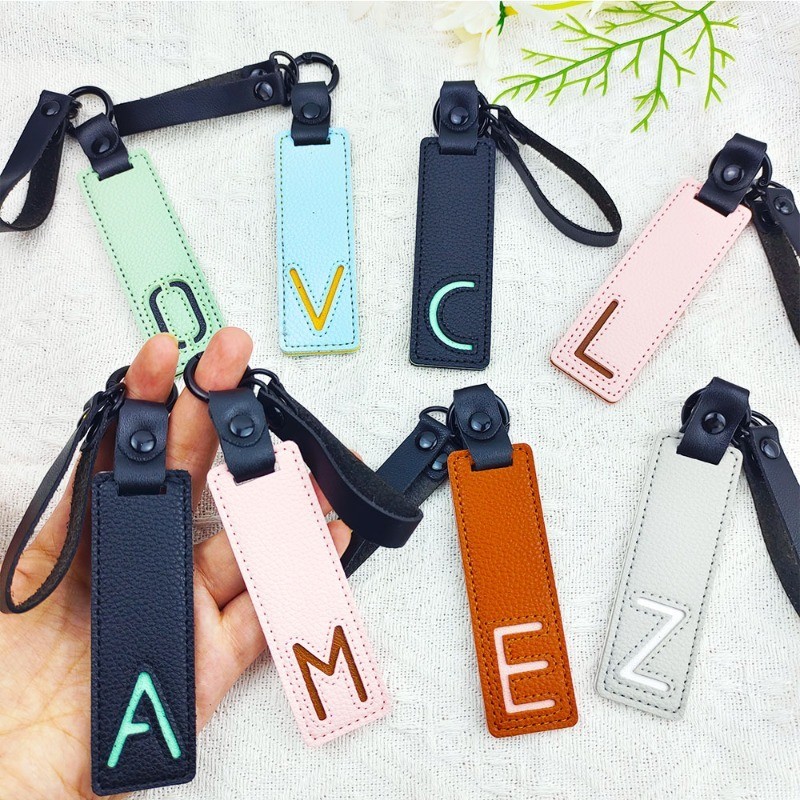 Monogram Keychain Leather - พวงกุญแจหนัง PU คลาสสิก A-Z พวงกุญแจเสน่ห์ขนาด26ชื่อย่อพร้อมสายรัดข้อมือแบบสั้นกระเป๋าเป้สะพายหลังใช้ได้ทั้งชายและหญิงอุปกรณ์จี้ห้อยกระเป๋าถือ